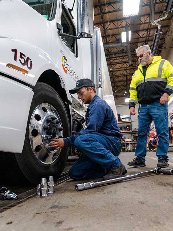 Trucker and technician servicing truck tire