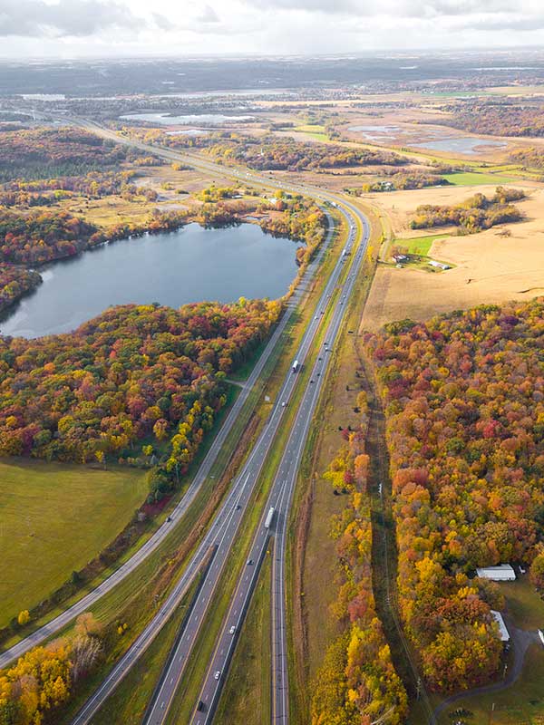 Long highway in fall with cars and trucks